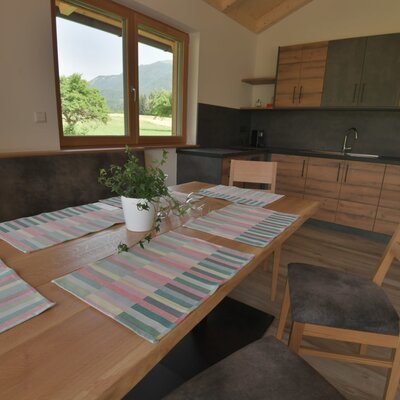 Die moderne Küchenzeile und der Essbereich mit Holztisch und Sitzbank bieten einen Ausblick auf die Landschaft des Bauernhofs.