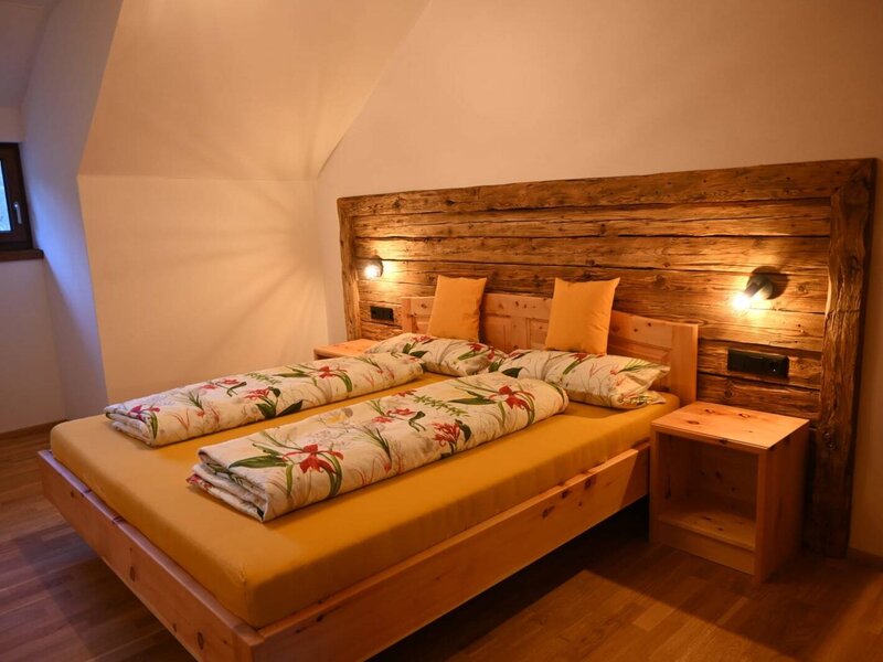 Schlafzimmer der Ferienwohnung mit Doppelbett, Holzkopfteil, Nachttischen, Leselampen und Fenster.