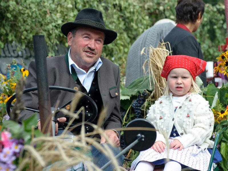 Traditionelle Tracht und ein liebevoll geschmückter Traktor versprühen ländlichen Charme auf dem Bauernhof.