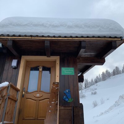Der Eingang zur Ferienwohnung Suntinger auf dem Bauernhof, erkennbar am Namensschild und umgeben von winterlichem Schnee.