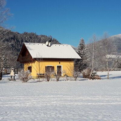 Das Gebäude des Bauernhofs inmitten einer verschneiten Winterlandschaft mit Bergen und Bäumen.
