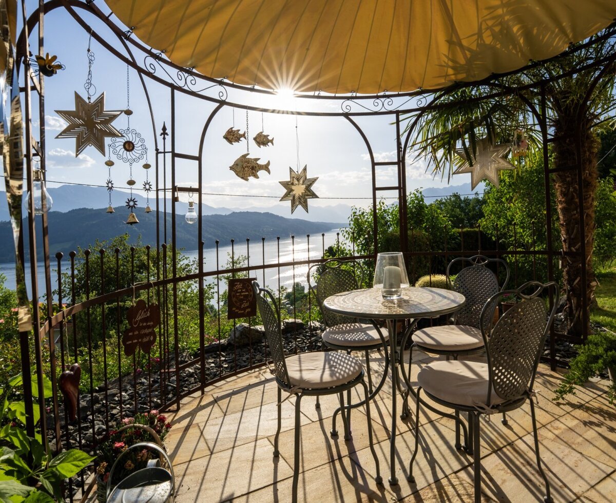 Sitzbereich im Freien unter einem Pavillon des Bauernhofs mit Blick auf den Millstätter See und die Berge.