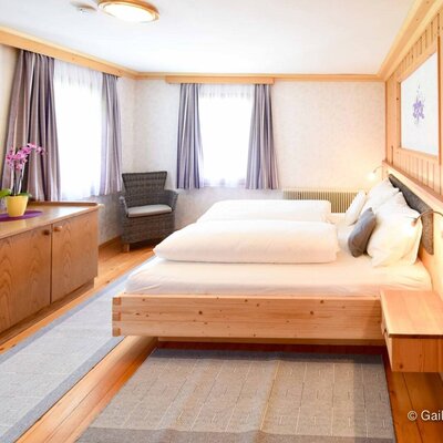Ein helles, freundliches Schlafzimmer der Ferienwohnung auf dem Bauernhof mit einem gemütlichen Doppelbett aus Holz und viel natürlichem Licht.