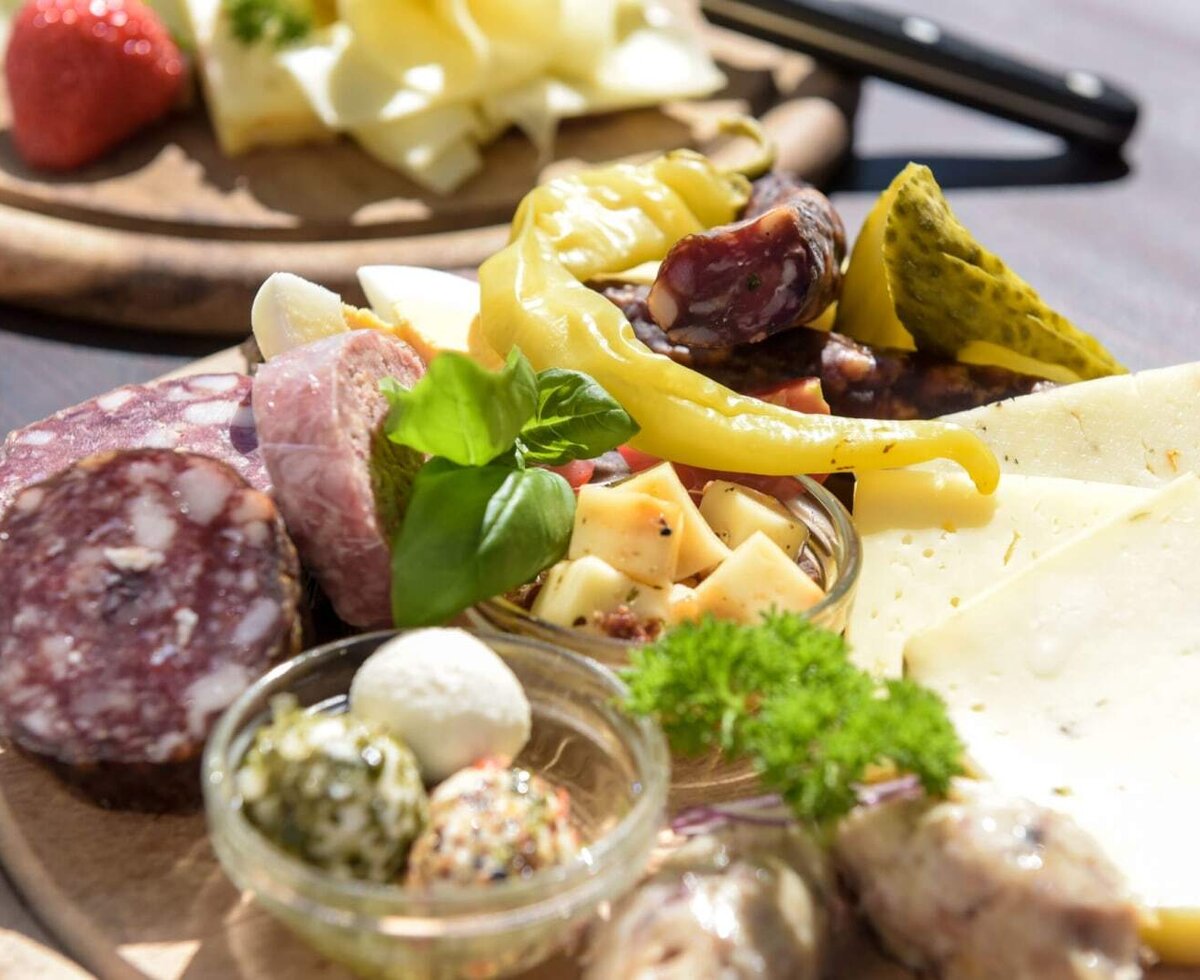 Eine reichhaltige Jausenplatte des Bauernhofs mit feinem Käse, herzhafter Wurst und frischen Kräutern.