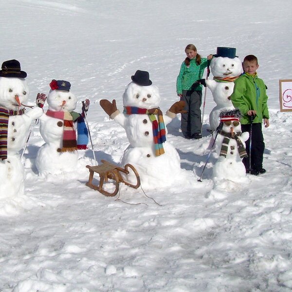 Eine Reihe von Schneemännern und Kinder im Schnee, mit einem Wegweiser zum Bauernhof Glautschhof.