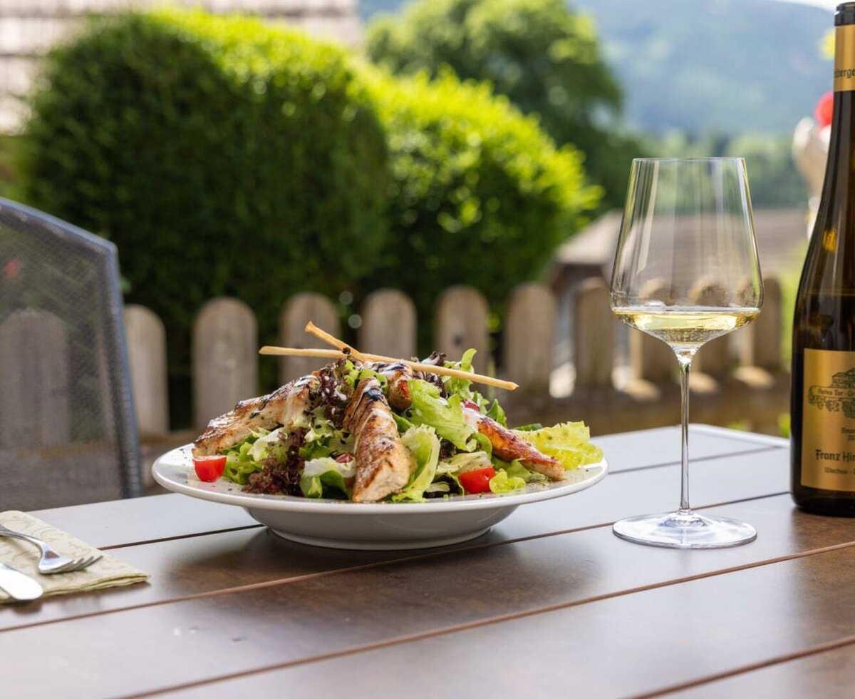Salat mit gegrilltem Hähnchen und Weißwein auf einem Holztisch im Außenbereich des Bauernhofs.