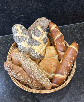 Ein einladender Korb mit frischen, ofenwarmen Brötchen und Gebäcksorten für ein gemütliches Frühstück in der Ferienwohnung.