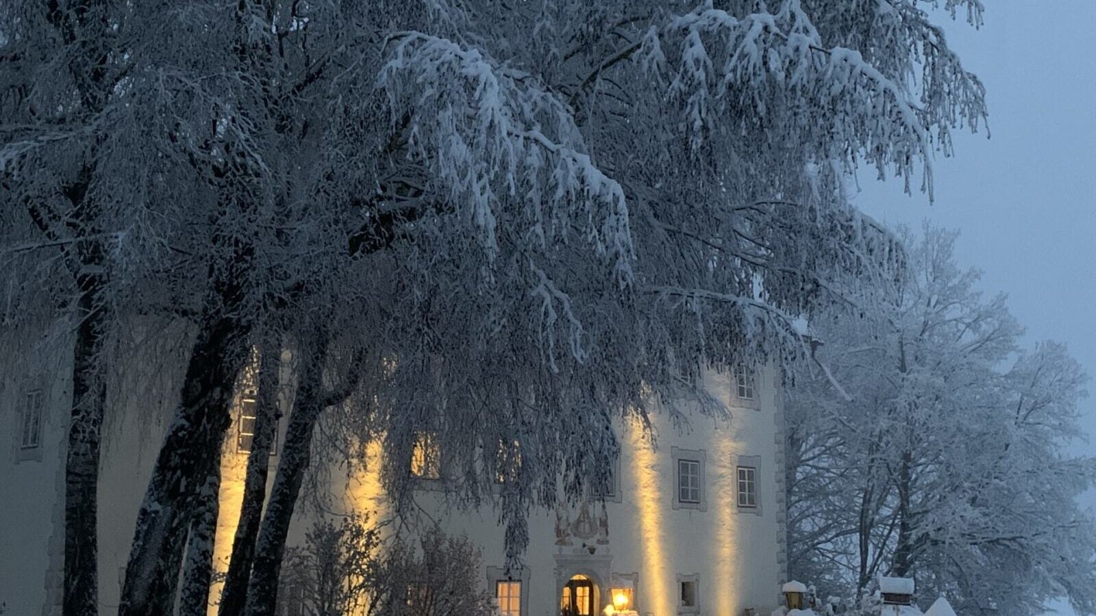 Das stimmungsvoll beleuchtete, historische Gebäude der Ferienwohnung inmitten einer verschneiten Winterlandschaft.