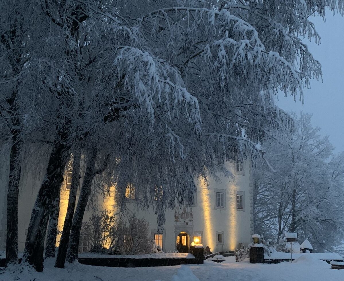 Das stimmungsvoll beleuchtete, historische Gebäude der Ferienwohnung inmitten einer verschneiten Winterlandschaft.