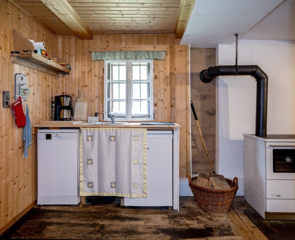 Die gemütliche Küche der Alm mit uriger Holzverkleidung, modernen Geräten und einem traditionellen Holzofen.
