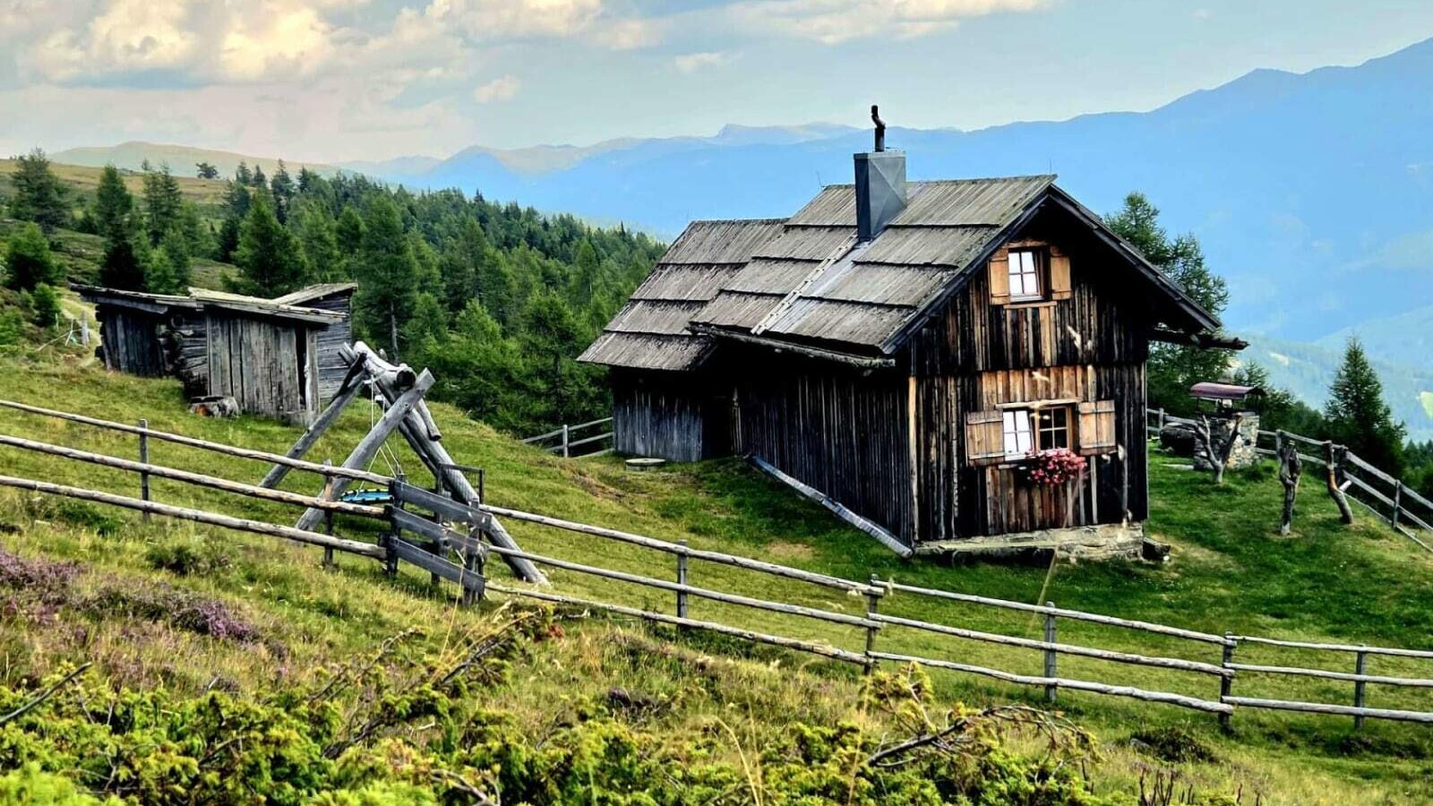 Die urige Alm liegt inmitten einer idyllischen Berglandschaft mit weiten Wiesen und einem weitreichenden Ausblick.