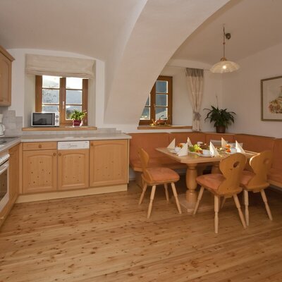 Die komplett ausgestattete Küche des Bauernhofs verfügt über einen Herd, Backofen, Mikrowelle, Geschirrspüler und eine Kaffeemaschine, ergänzt durch einen Essbereich mit Holztisch und Eckbank.