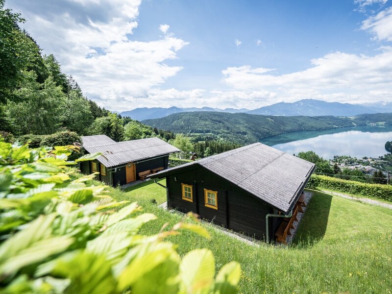 Mehrere Ferienhäuser am Hang mit Blick auf den See und die umliegenden Berge.