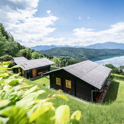 Mehrere Ferienhäuser am Hang mit Blick auf den See und die umliegenden Berge.