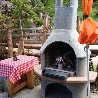 Ein einladender Steingrill auf der Terrasse der Alm, ideal für gemütliche Grillabende inmitten der Natur.