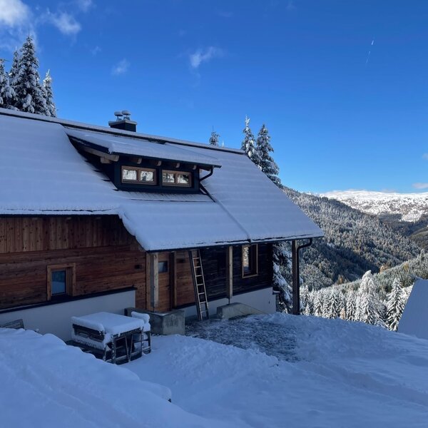 Die traditionelle Alm, eingebettet in eine verschneite Winterlandschaft mit malerischem Bergblick.