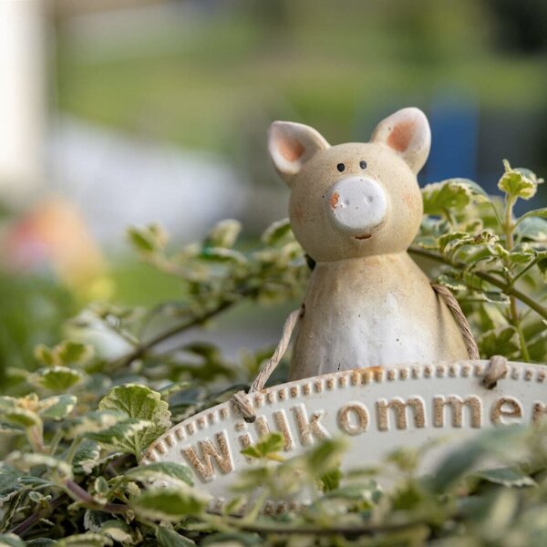 Eine Keramikschwein-Figur mit einem "Willkommen"-Schild begrüßt die Gäste auf dem Bauernhof.