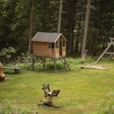 Spielplatz der Alm mit Stelzen-Spielhaus und Federwippe.