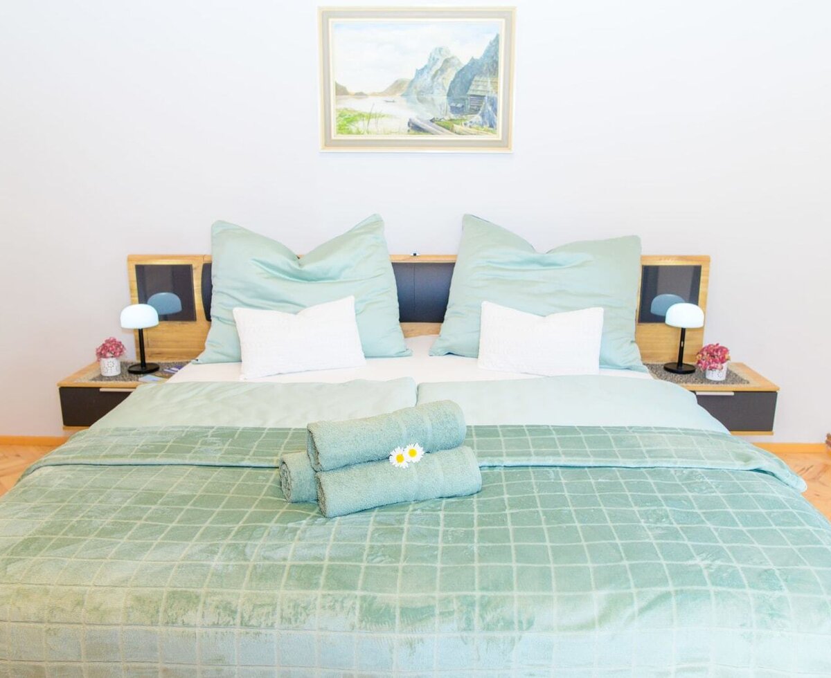 Doppelzimmer im Bauernhof mit einem Doppelbett, zwei Nachttischen, Leselampen und gerollten Handtüchern.