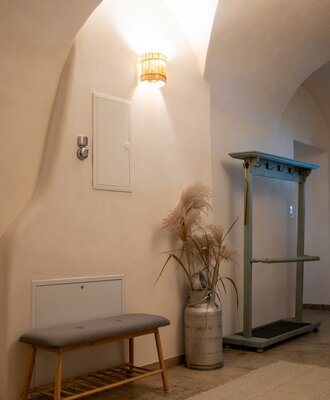 Der Eingangsbereich des Bauernhofs verfügt über eine Gewölbedecke, eine Holzbank und eine Garderobe.