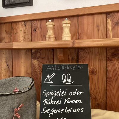 Eine Tafel auf dem Bauernhof informiert über die Möglichkeit, Spiegelei oder Rührei zum Frühstück zu bestellen.