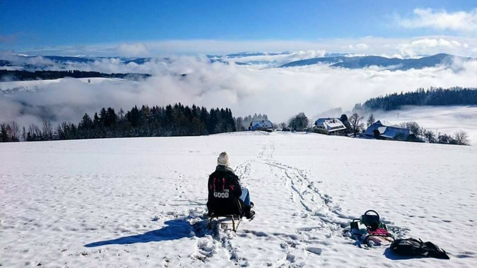 Die verschneite Landschaft des Bauernhofs mit Blick auf die Karawanken und nebelverhangene Täler, ideal zum Rodeln.