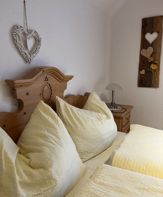 Schlafzimmer im Bauernhof mit Holzdoppelbett, Nachttisch und Lampe im bäuerlichen Stil.