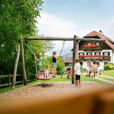 Kinderspielplatz des Bauernhofs mit Schaukeln und weiteren Spielgeräten.