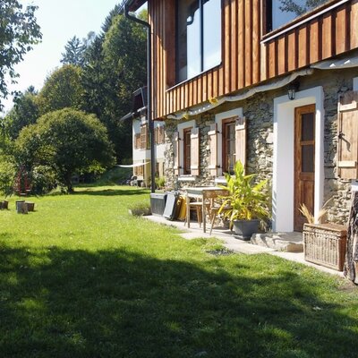 Der Garten des Bauernhofs mit einer großen Rasenfläche, einem Picknicktisch und einer Terrasse mit Sitzgelegenheiten.