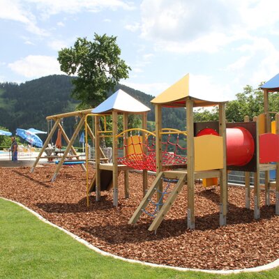 Spielplatz mit Schaukel, Rutsche, Klettergerüst und Röhre für die Ap­par­te­ments.