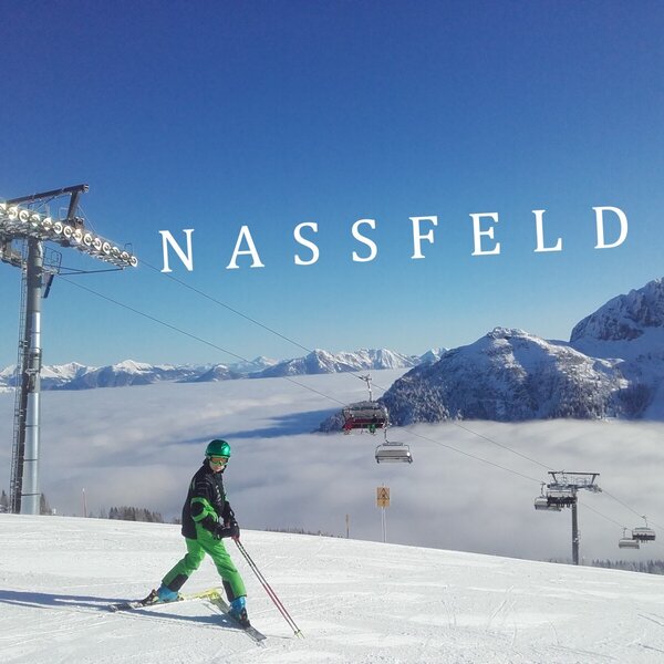 Wintersportmöglichkeiten in Nassfeld mit einem Skifahrer auf der Piste und einem Bergpanorama über den Wolken.
