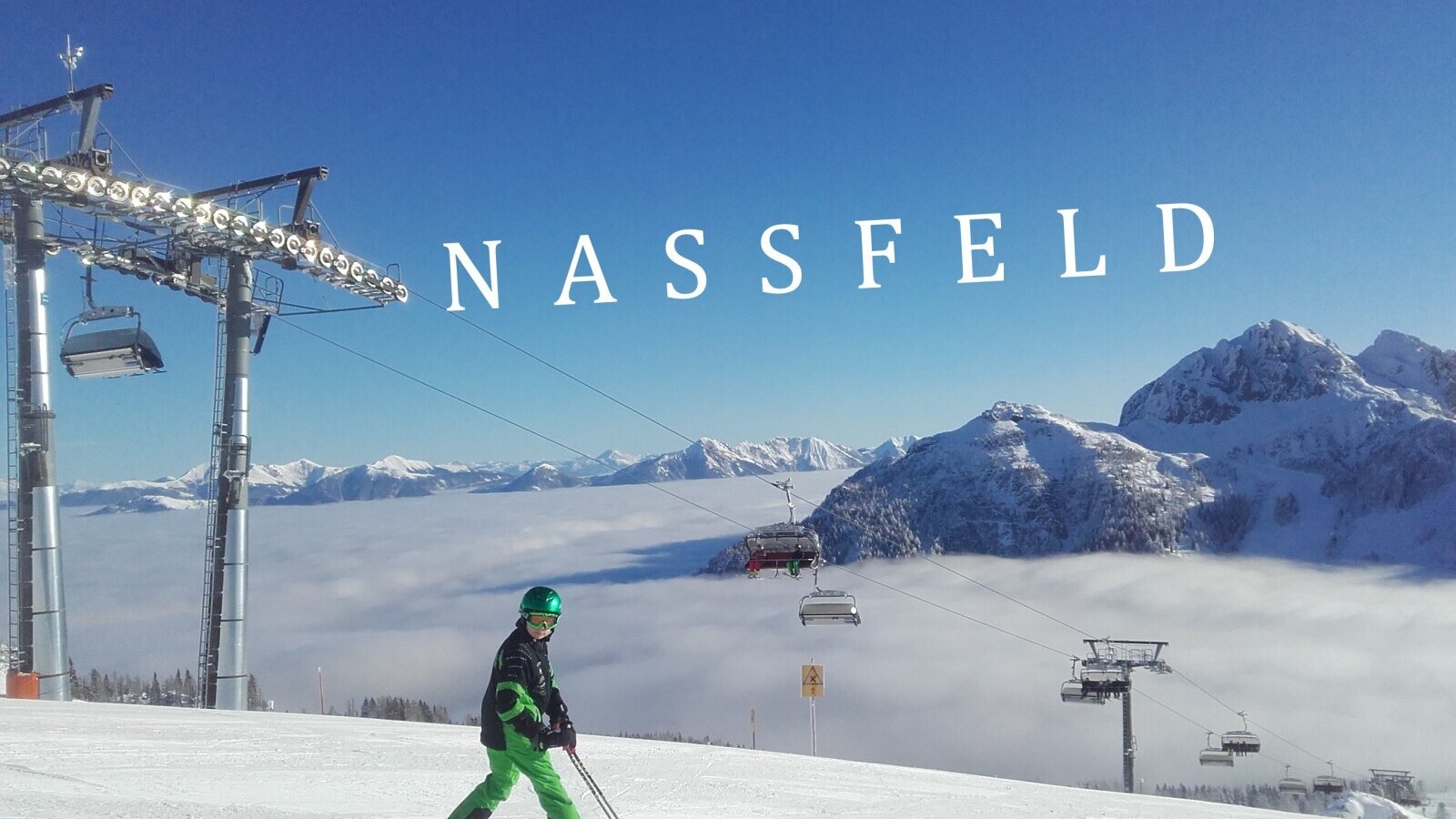 Wintersportmöglichkeiten in Nassfeld mit einem Skifahrer auf der Piste und einem Bergpanorama über den Wolken.
