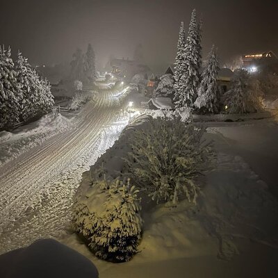 Die nächtliche, verschneite Umgebung des Bauernhofs mit beleuchteter Straße.