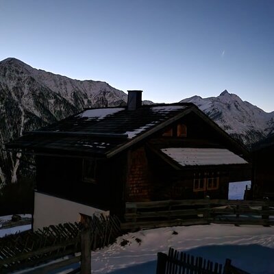 Die Almhütte im Schnee mit Blick auf die umliegenden Berge.