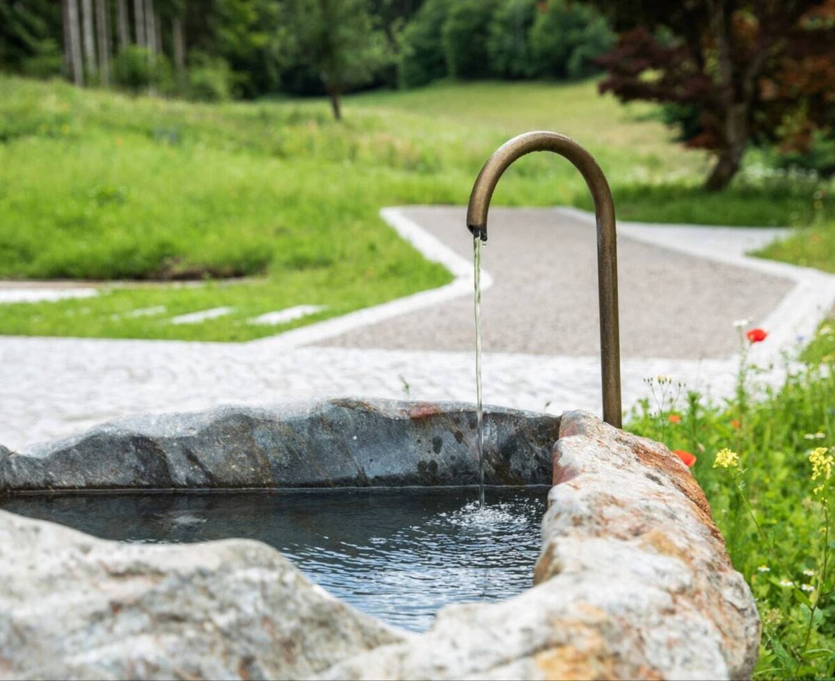 Ein charmanter Steinbrunnen mit fließendem Wasser im einladenden Gartenbereich der Ferienwohnung.