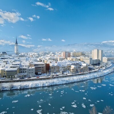 Winteransicht der Stadt Villach mit der Drau und schneebedeckten Bergen im Hintergrund, nur 5 km vom Bauernhof entfernt.