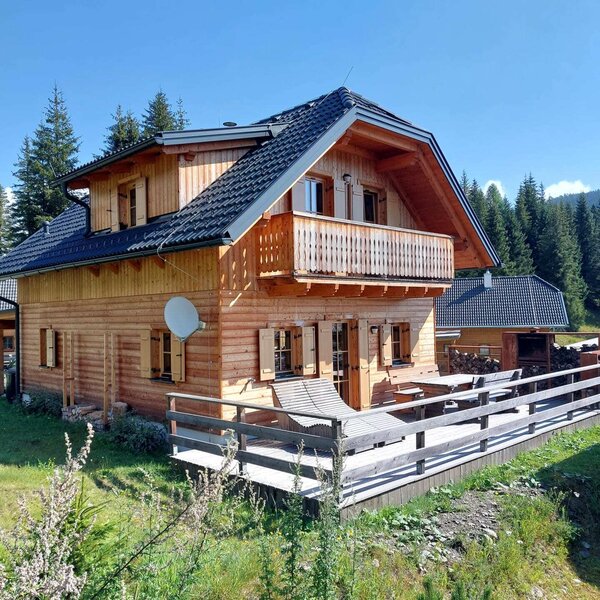 Die einladende Alm verfügt über eine sonnige Holzterrasse mit einem Liegestuhl und einen gemütlichen Balkon mitten im Grünen.