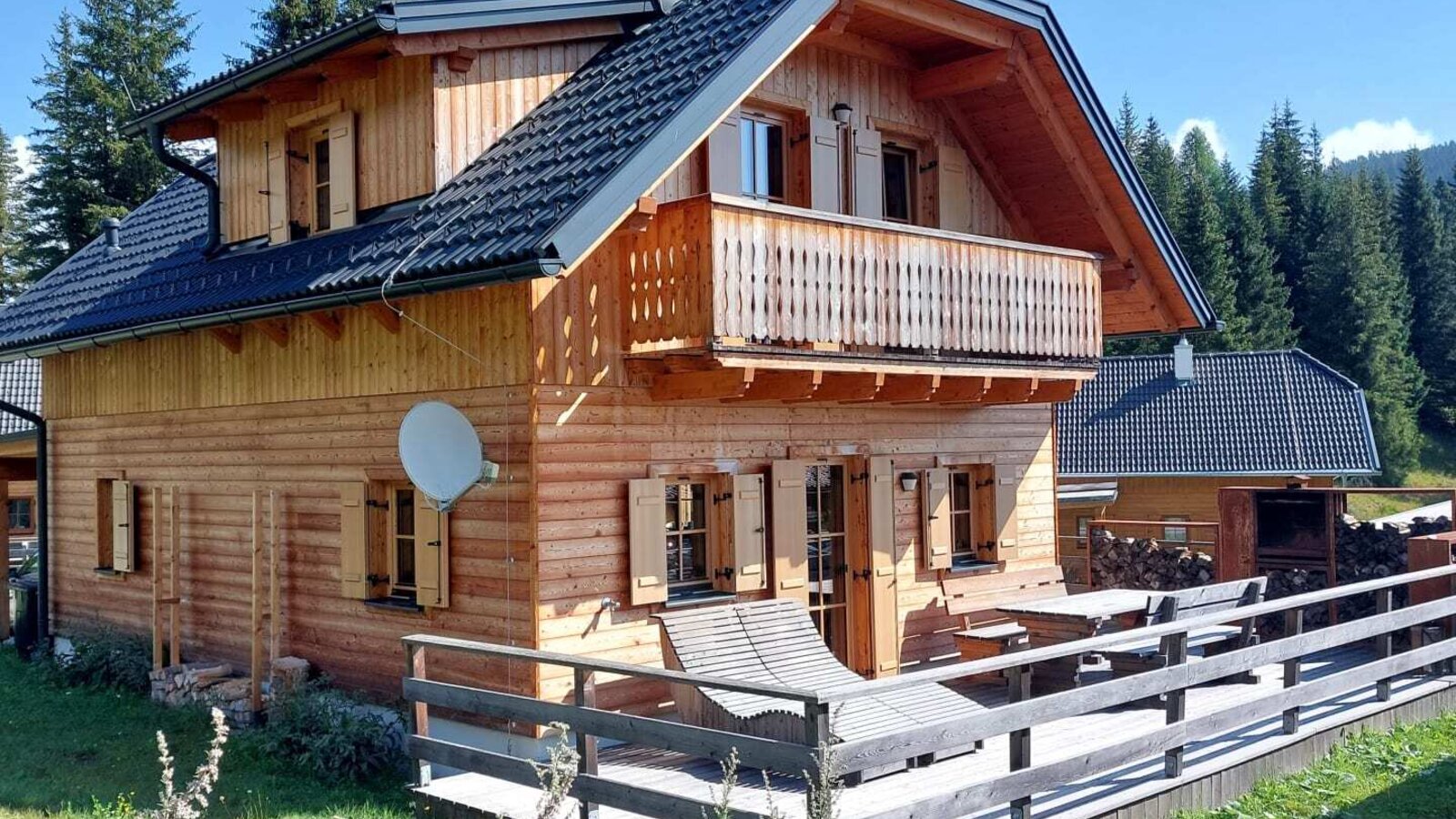 Die einladende Alm verfügt über eine sonnige Holzterrasse mit einem Liegestuhl und einen gemütlichen Balkon mitten im Grünen.
