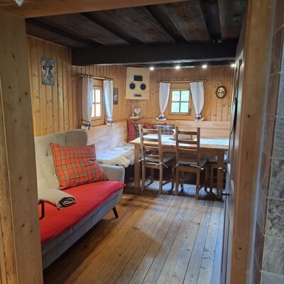 Die heimelige Wohnküche der Hütte mit einer gemütlichen Sitzecke, einem Sofa und traditioneller Holzvertäfelung.