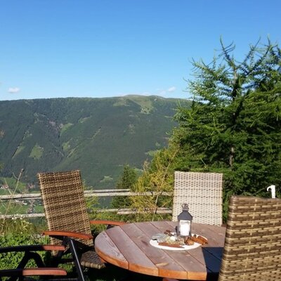 Der einladende Außenbereich der Hütte mit gemütlichen Sitzgelegenheiten und einem herrlichen Ausblick auf die umliegende Berglandschaft.
