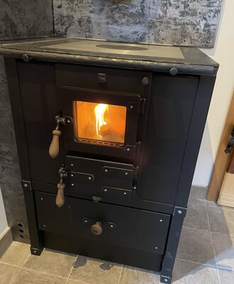 Der traditionelle Holzofen im Ferienhaus mit sichtbarem Feuer dient als Kamin und Kochgelegenheit.