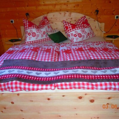 Doppelzimmer in der Alm mit Zirbenbett und traditioneller Bettwäsche.
