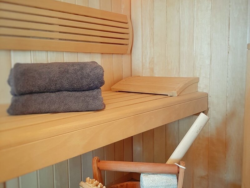 Eigene Sauna des Apartments im Hof mit Holzbänken, Handtüchern und Saunazubehör.