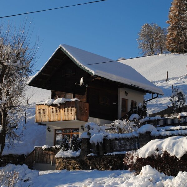 Das Ferienhaus von außen, im Winter mit schneebedecktem Dach und Balkon.