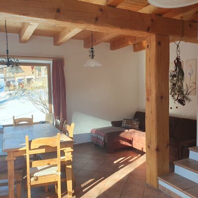 Wohnbereich des Bauernhofs im rustikalen Landhausstil mit Esstisch, Sofa und Blick nach Draußen