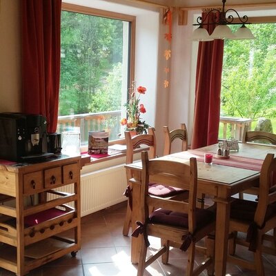 Die großzügige Wohnküche des Bauernhofs mit Esstisch, Stühlen, Kaffeemaschine und Zugang zur Terrasse mit Blick ins Grüne.