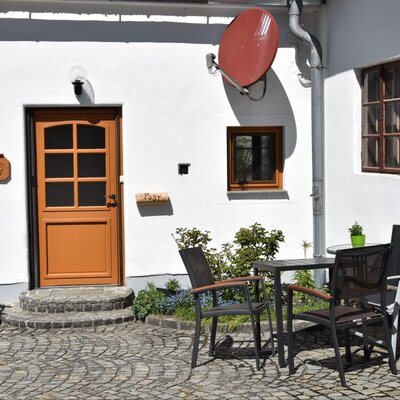 Innenhof der Ferienwohnung mit Tisch, Stühlen und Sonnenschirm.