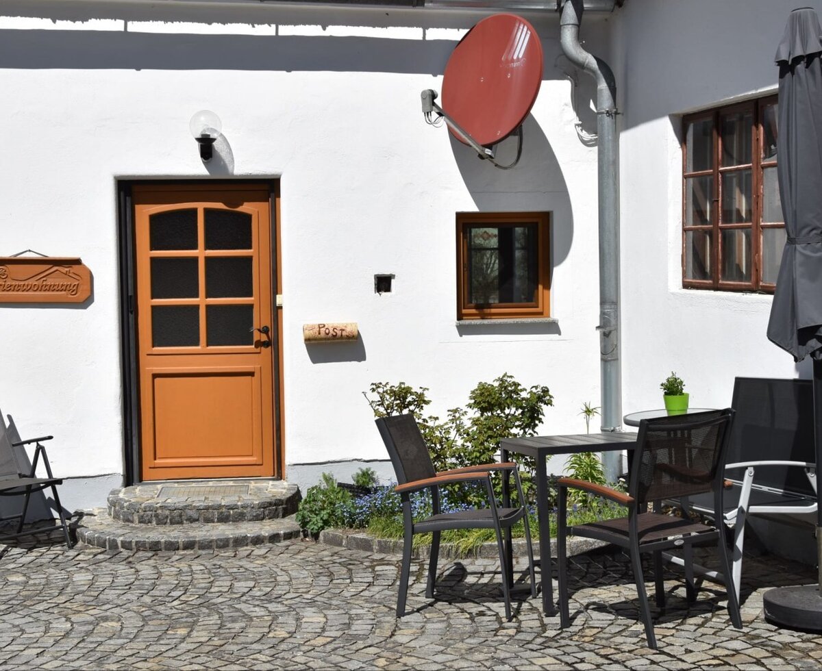 Innenhof der Ferienwohnung mit Tisch, Stühlen und Sonnenschirm.