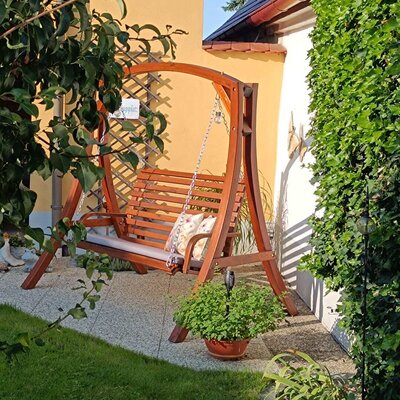 Gartenschaukel aus Holz mit Kissen im Innenhof.