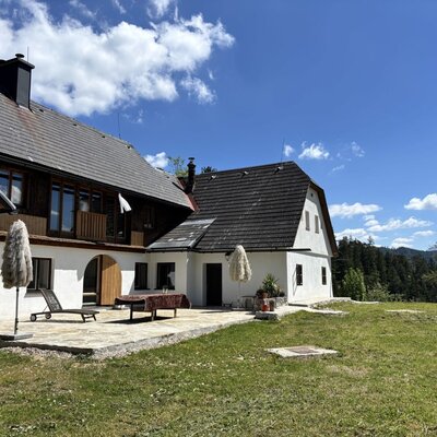 Außenansicht mit Terrasse, Liegestuhl und Blick auf die Berge und Wälder.